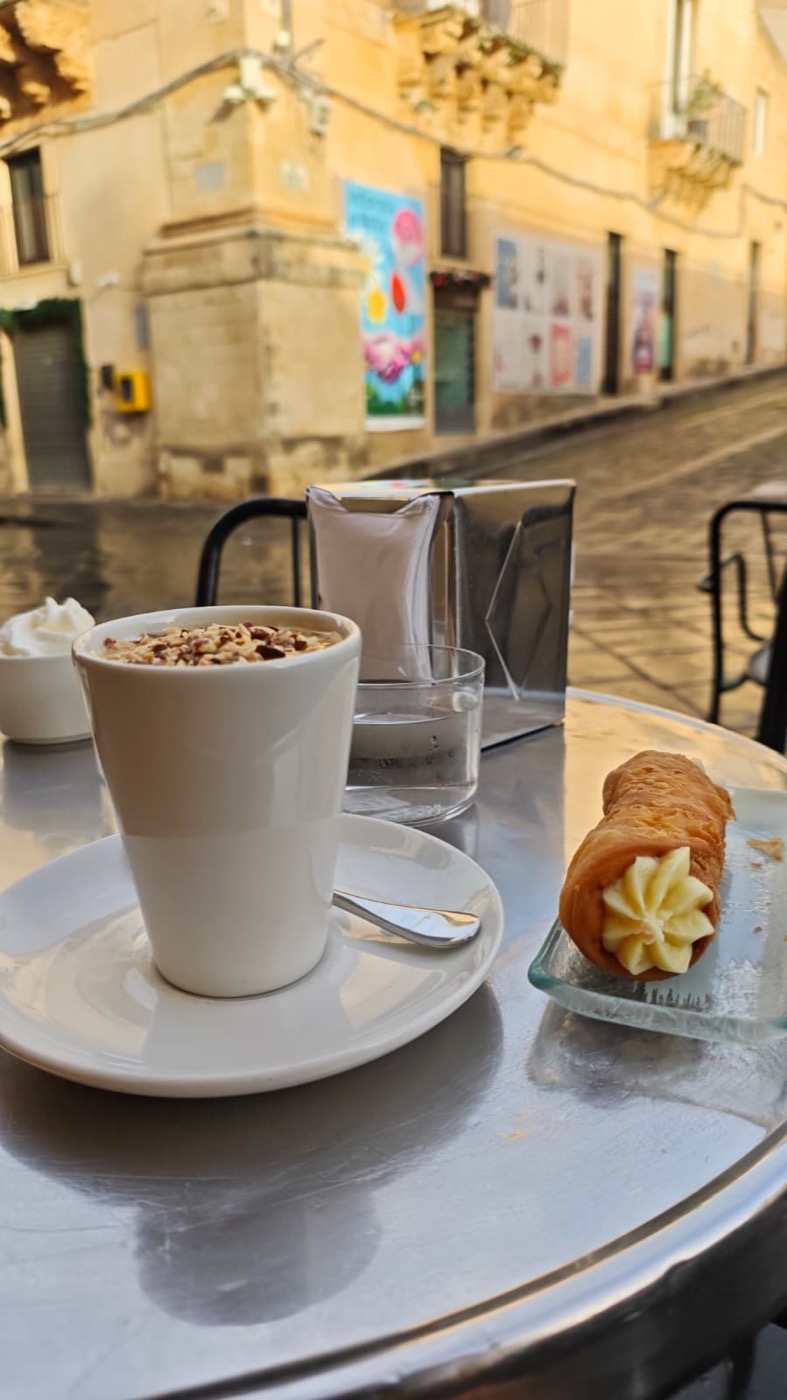 Granita di mandorla with a cannolino at Caffe Sicilia, Noto's Baroque street behind