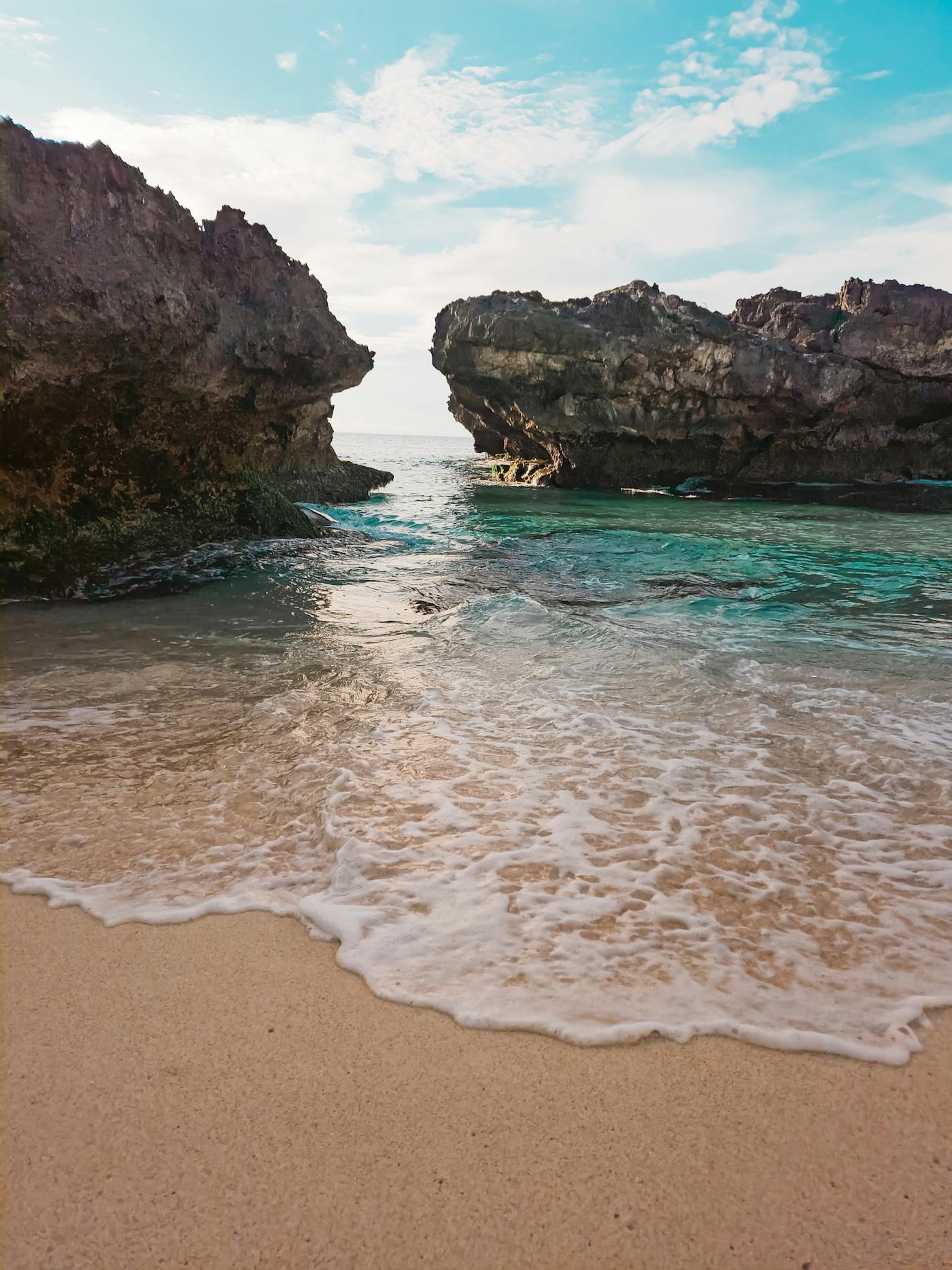 Turquoise water in a sheltered sandy cove between rocky headlands