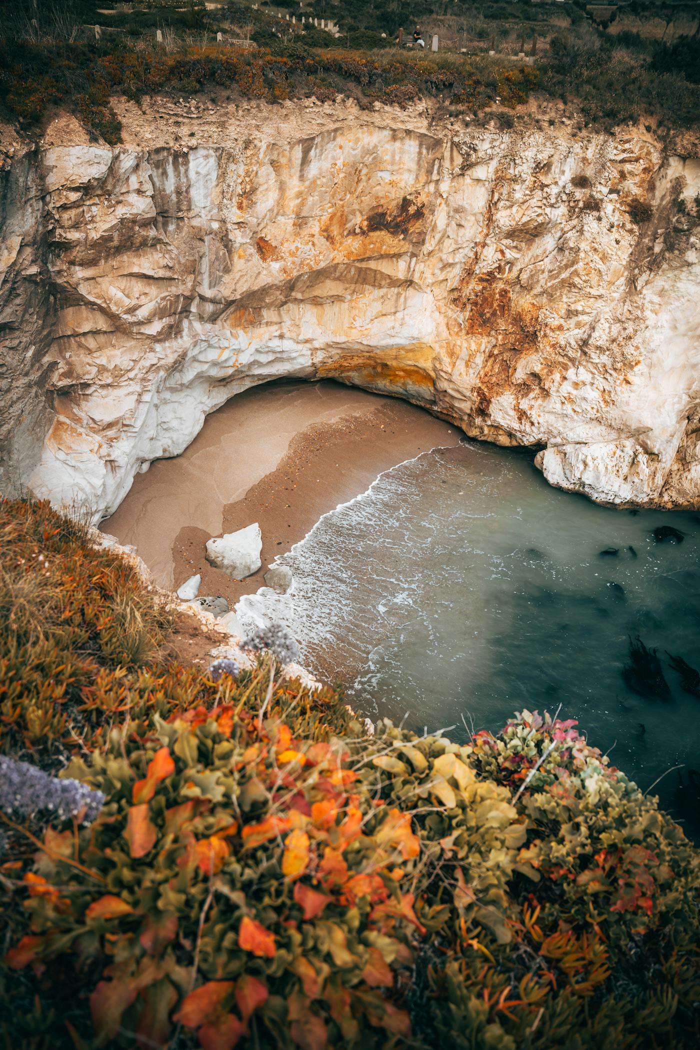 Sandy beach cove with clear shallow water between natural rock formations
