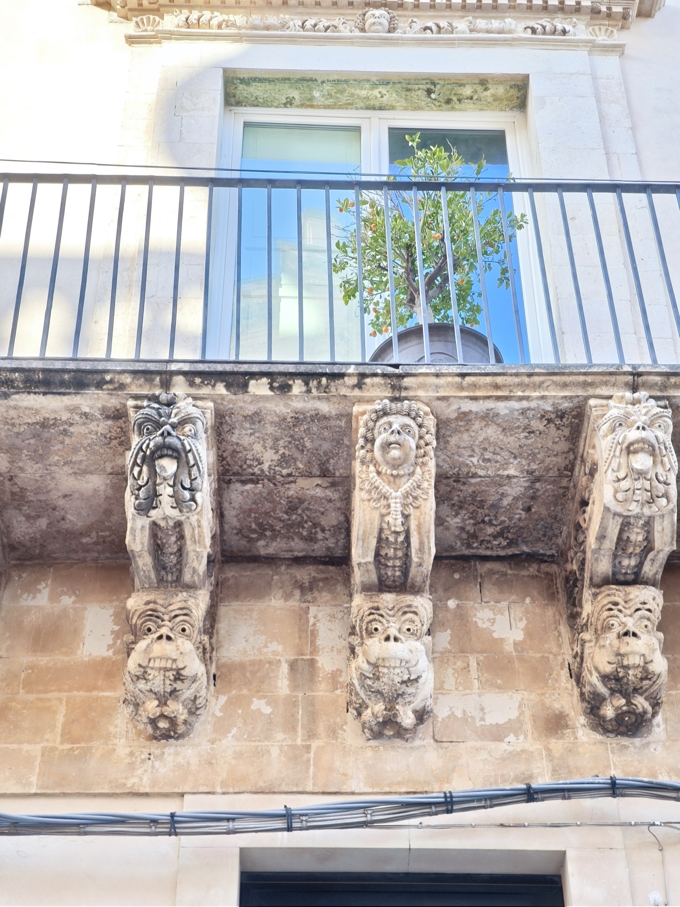 Ornate carved stone corbels supporting a Baroque balcony on Palazzo Nicolaci in Noto