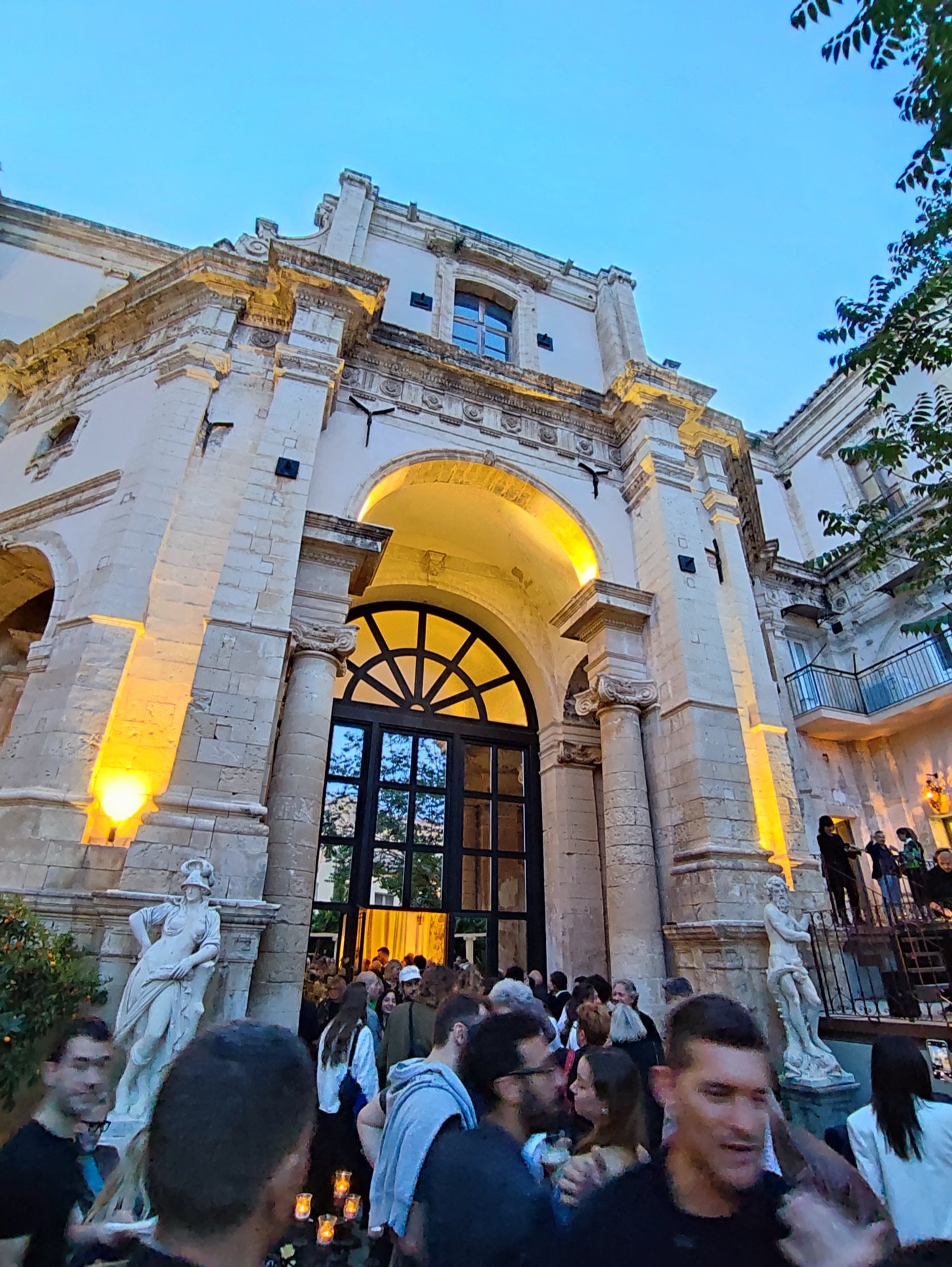 Grand Baroque palazzo illuminated at dusk with warm uplighting and evening crowds