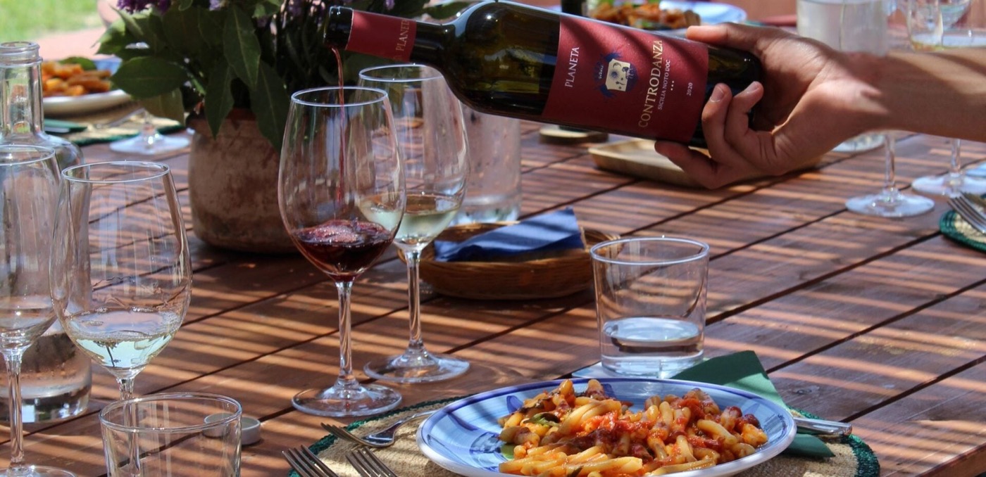 Long table lunch among the vines at a Contrada Buonivini estate — wine, bread, and local Sicilian dishes