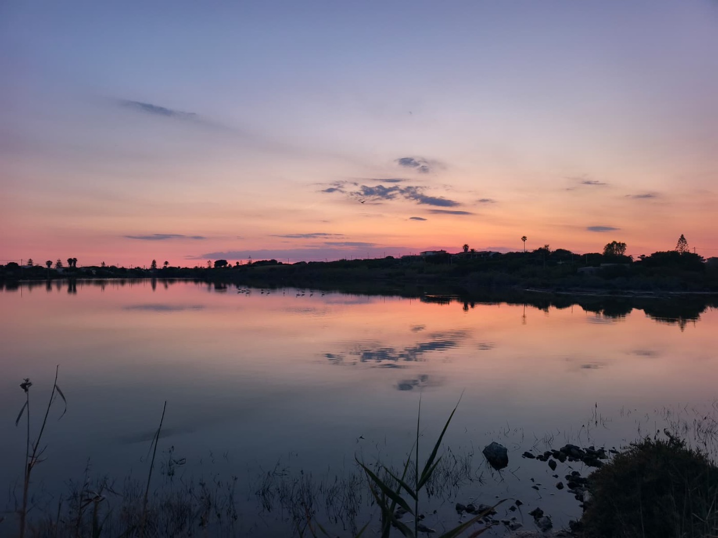 Pink and blue sunset reflected in the mirror-still salt pans near Villa Magnus
