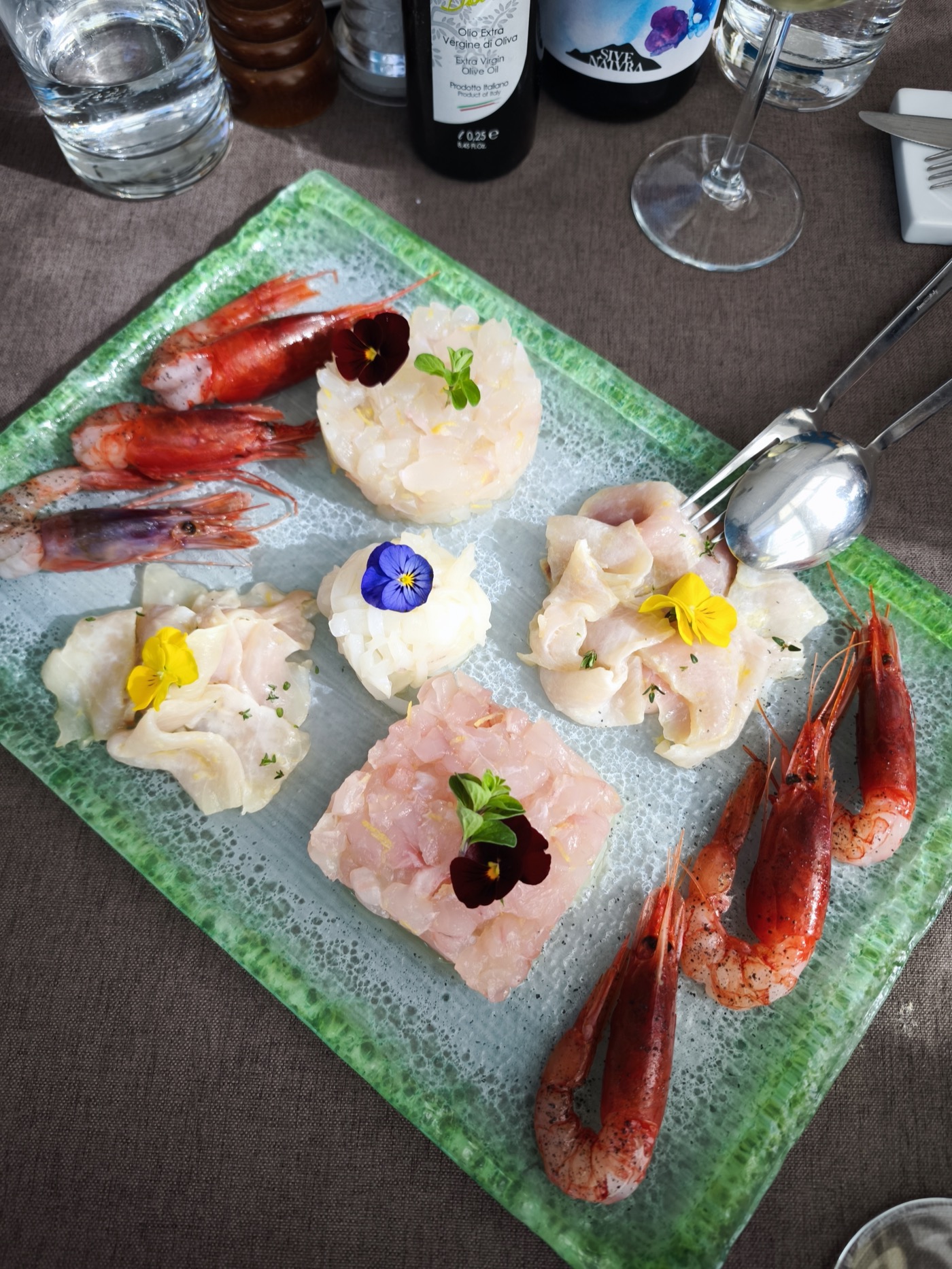 A platter of seafood crudo with red prawns, fish carpaccio, and edible flowers