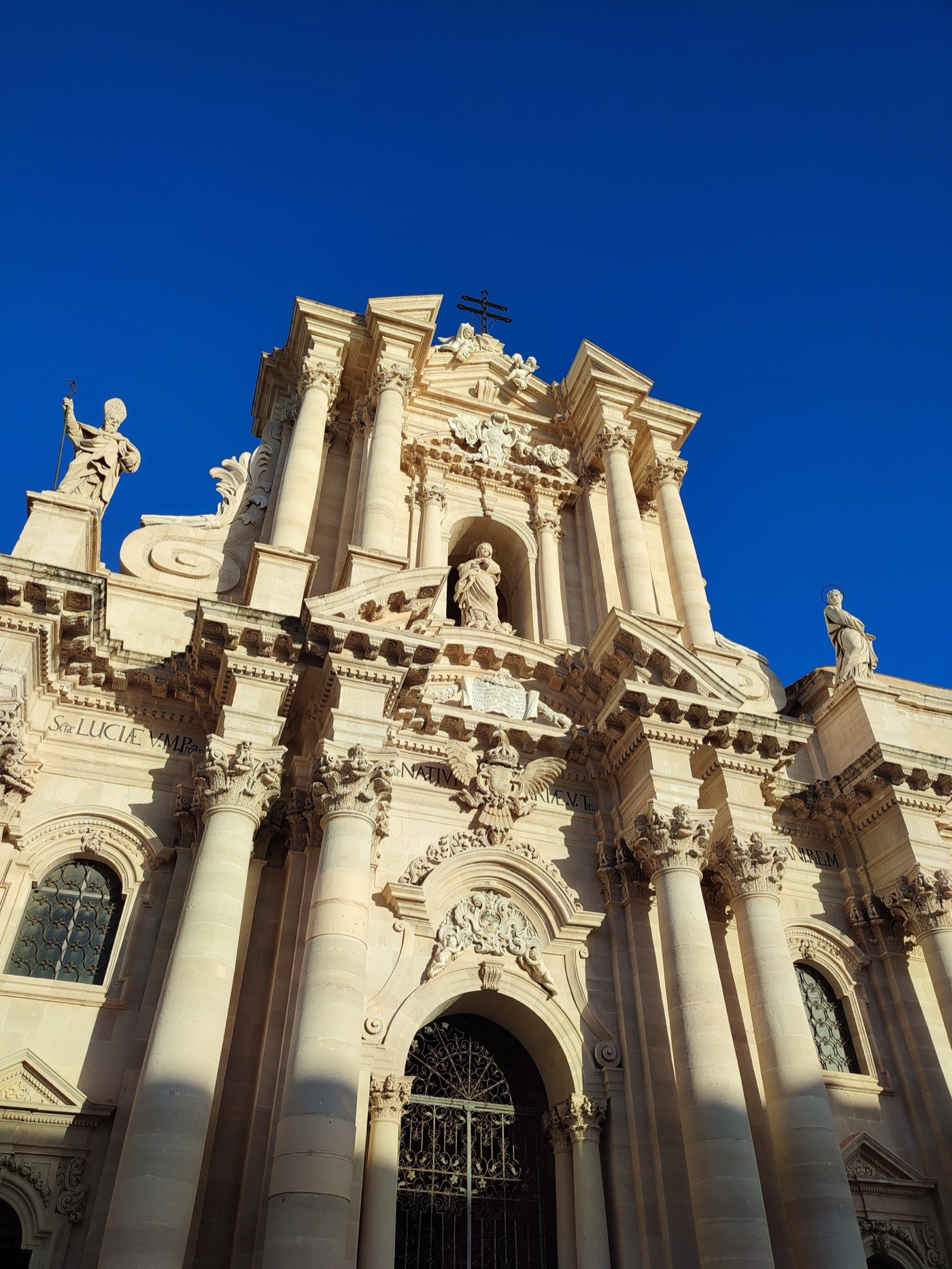 The Baroque facade of Siracusa Cathedral against a deep blue sky