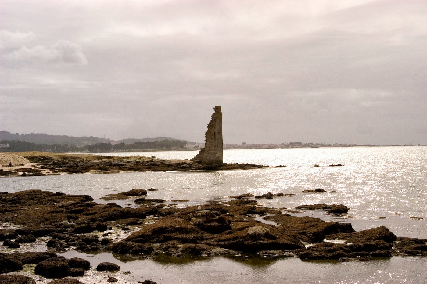 Ancient stone ruins on a rocky Mediterranean coastline under dramatic skies